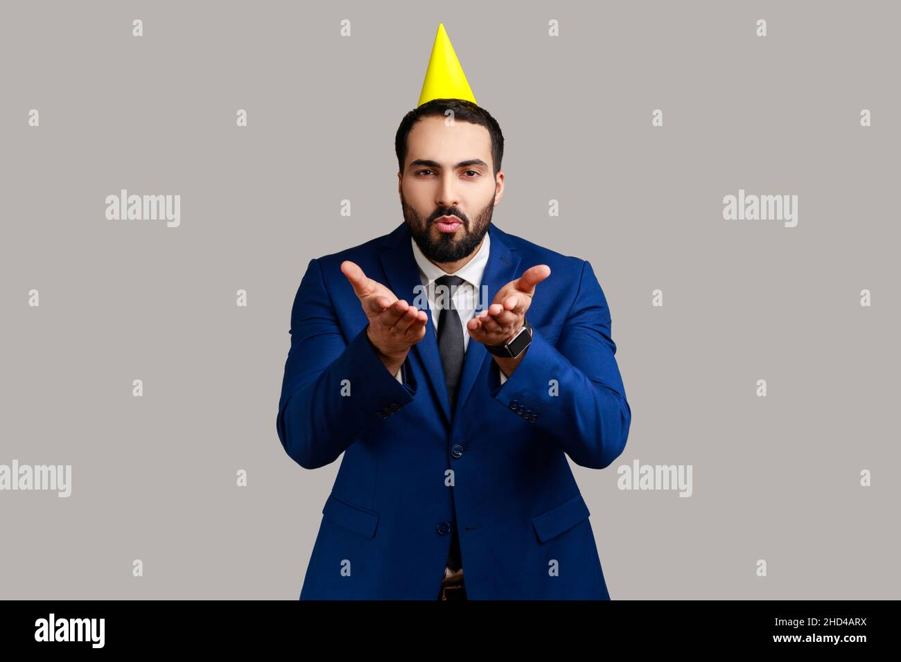 Homme d'affaires à la belle barbe romantique avec chapeau de fête envoyant un baiser d'air à la caméra, salutation de vacances, flirt, portant un costume de style officiel.Prise de vue en studio isolée sur fond gris. Banque D'Images Homme d'affaires à la belle barbe romantique avec chapeau de fête envoyant un baiser d'air à la caméra, salutation de vacances, flirt, portant un costume de style officiel.Prise de vue en studio isolée sur fond gris. Banque D'Images