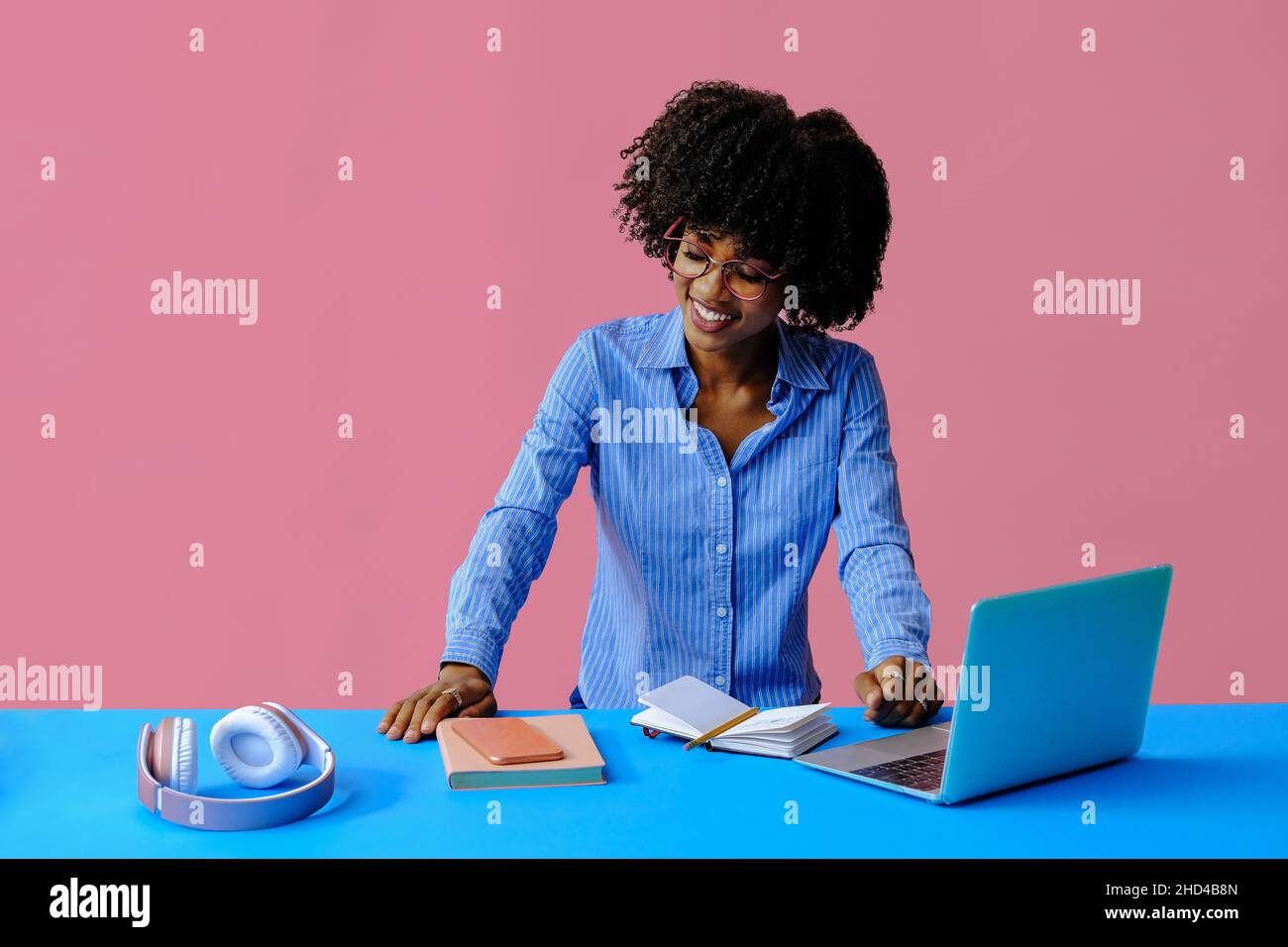 jeune femme d'affaires afro-américaine souriante qui regarde vers le bas sur le lieu de travail Banque D'Images