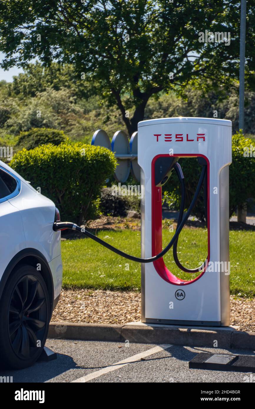 Grantham, Royaume-Uni - Mai 30th 2021 : compresseur Tesla dans une zone d'entretien d'autoroute avec un modèle blanc x.Photo de haute qualité Banque D'Images