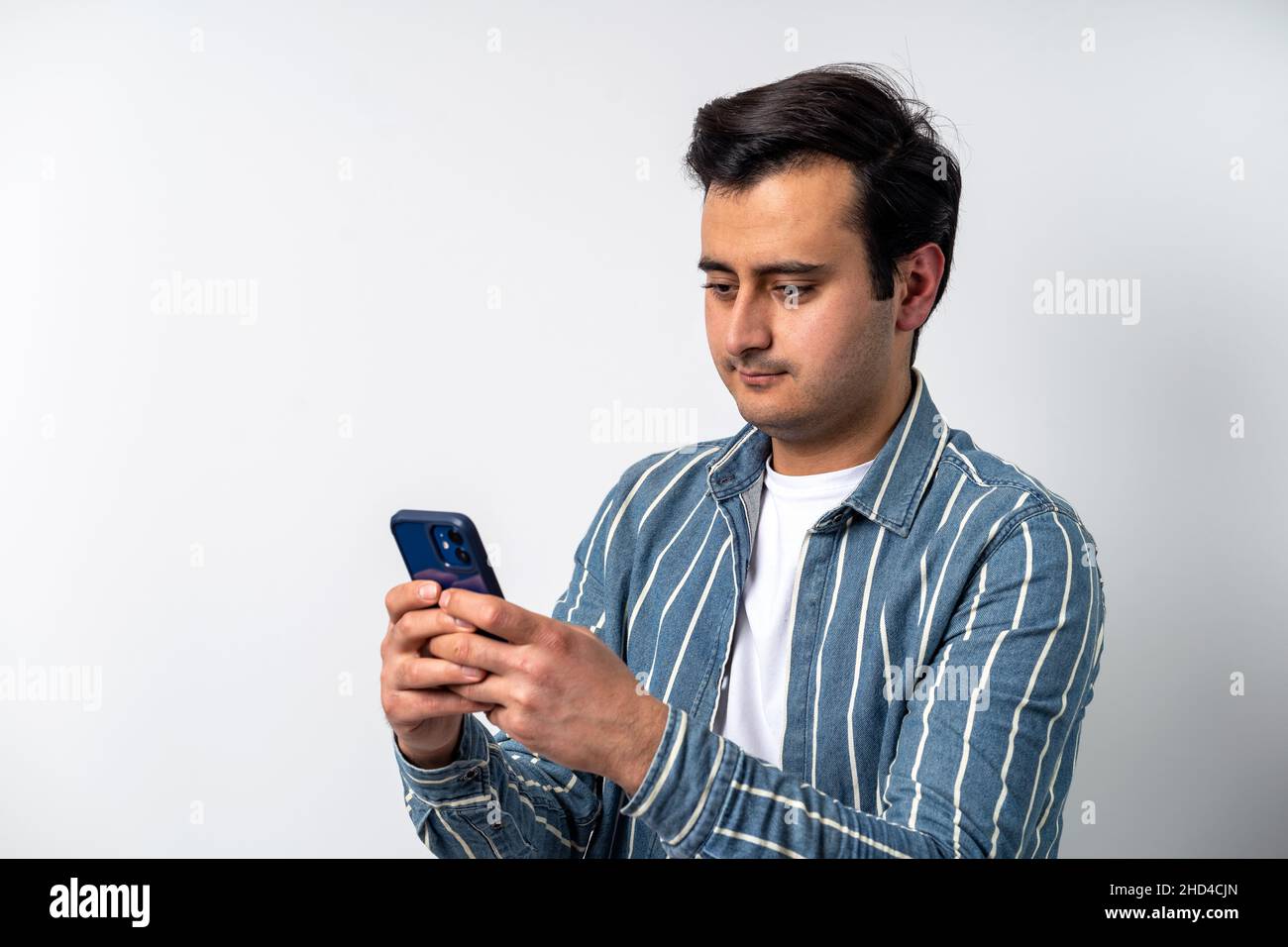 Gros plan d'un modèle de jeune adulte à la peau marron, envoi de SMS avec des amis sur les réseaux sociaux avec un smartphone sur un arrière-plan blanc isolé. Banque D'Images