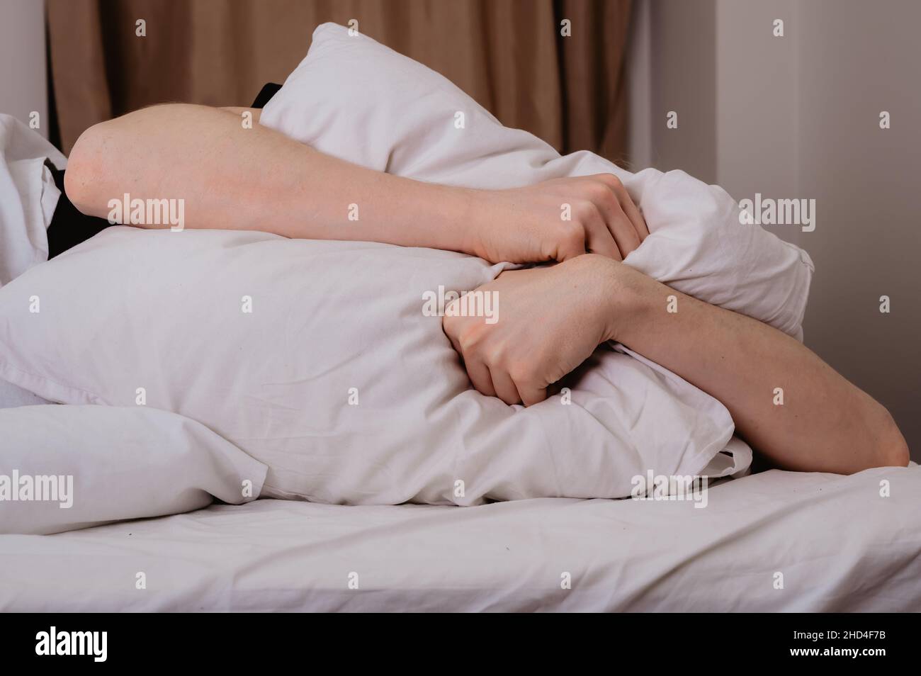 Homme déprimé couché seul dans le lit couvrant sa tête avec un oreiller, peur ou déprimé, souffrant d'insomnie, voisins forts, après un divorce de h Banque D'Images