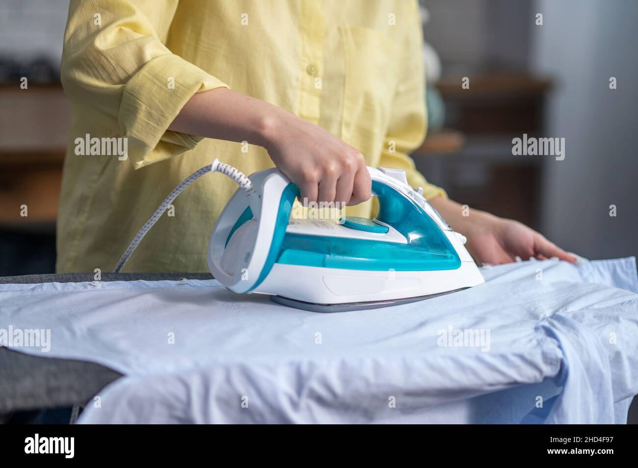 Les mains des femmes repassant des vêtements froissés sur la planche à repasser Banque D'Images