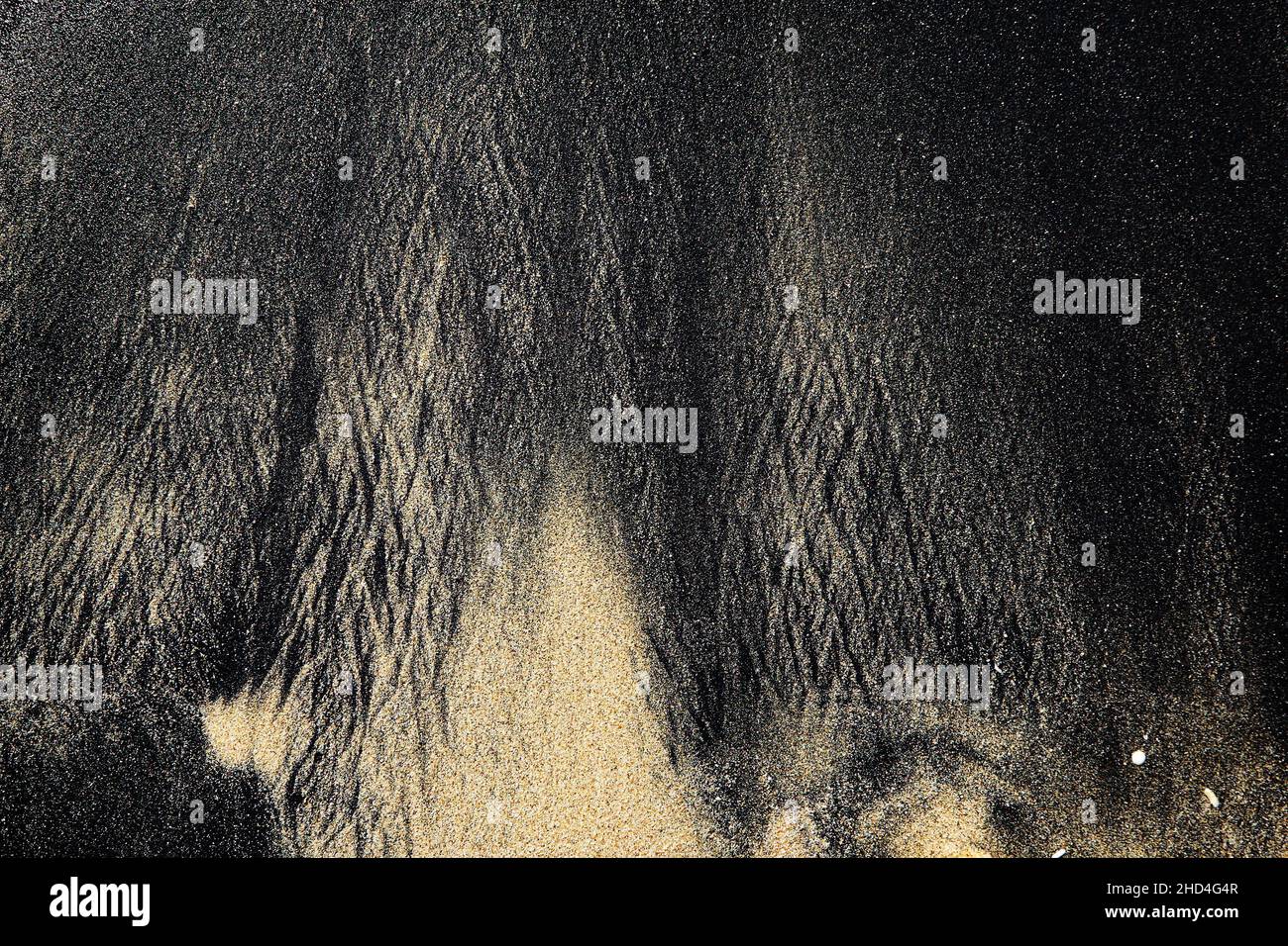 Motif abstrait fait par des vagues sur le sable noir volcanique de l'île de Bali Banque D'Images