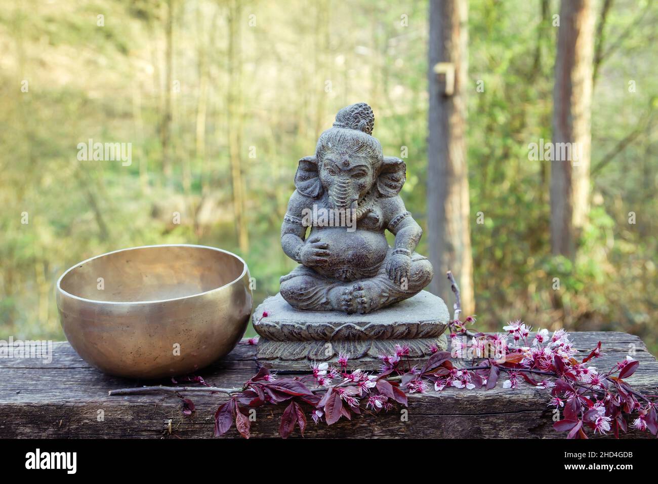 Bol de chant en sept métaux et statue en pierre décorative de Ganesh deyty dans le jardin. Banque D'Images