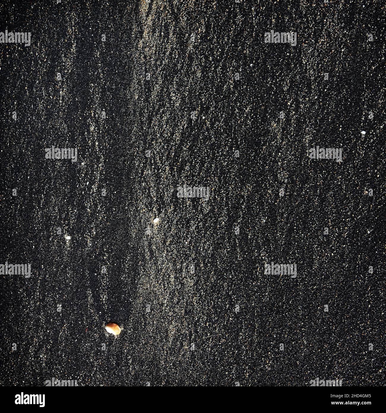 Motif abstrait fait par des vagues sur le sable noir volcanique de l'île de Bali Banque D'Images