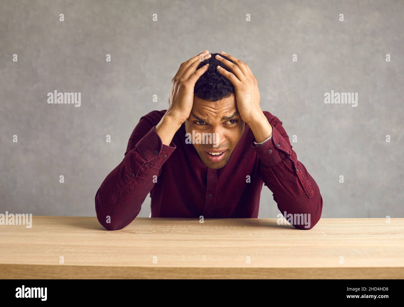 Un homme afro-américain désespéré tient la tête avec les mains assis au bureau studio tourné Banque D'Images