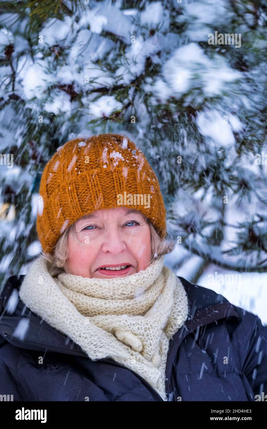 Femme d'âge moyen à l'extérieur en hiver avec un pin recouvert de neige Banque D'Images