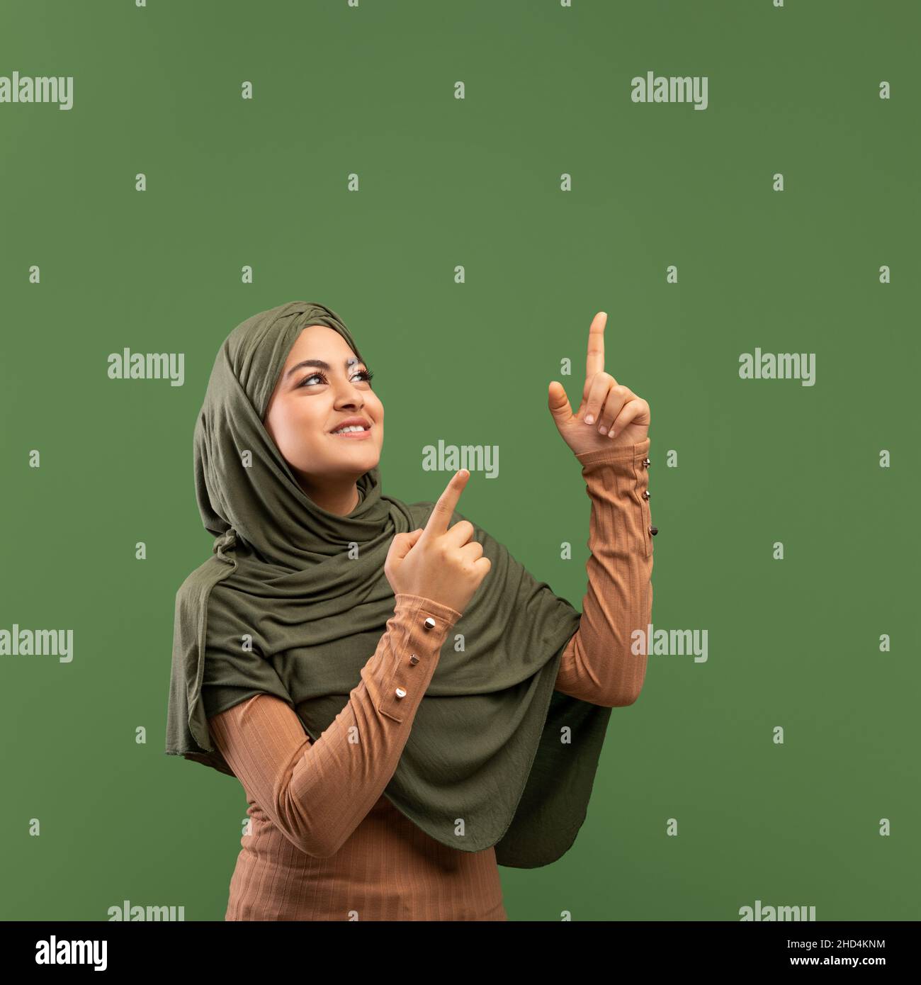 Vérifiez ceci.Bonne dame arabe pointant vers le haut à l'espace libre au-dessus de sa tête, démontrant la place libre pour votre annonce Banque D'Images