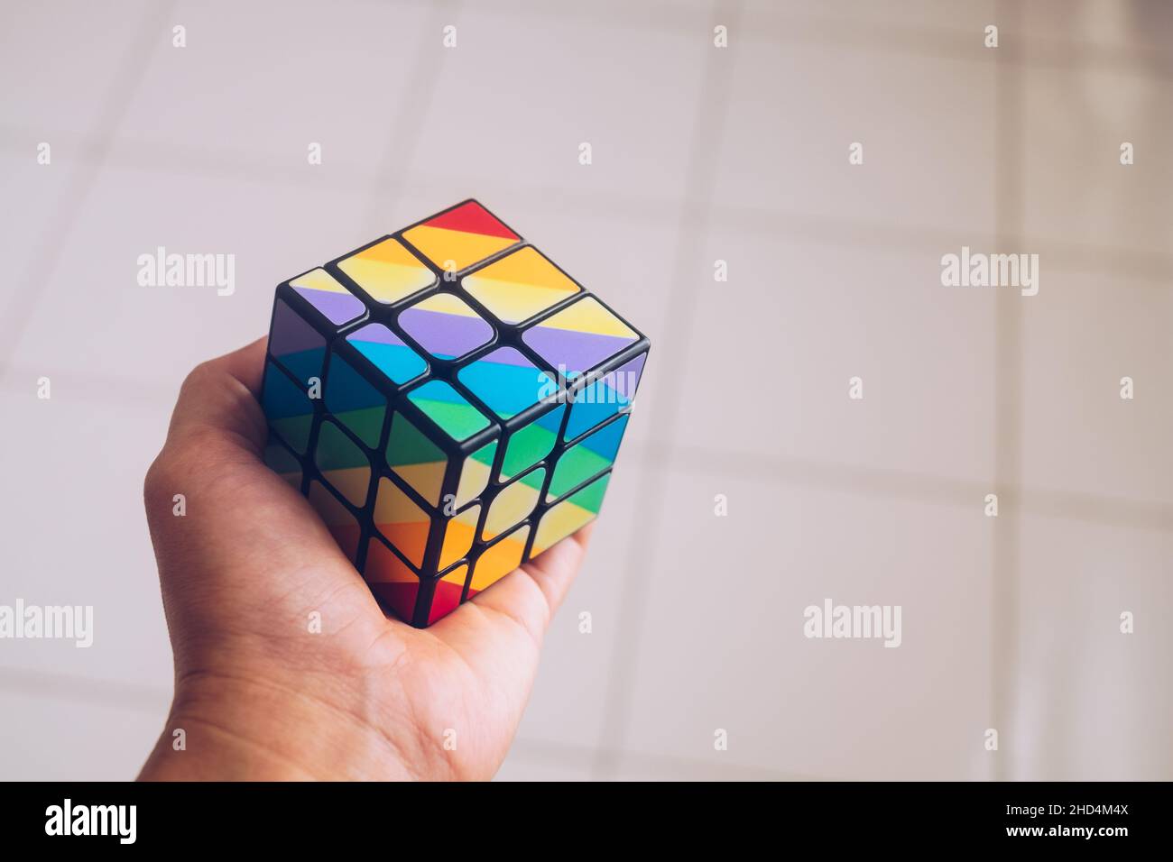 KORONADAL, pH – DEC 26, 2021 : le cube de Rubik a été inventé par Erno Rubik.Main tenant un motif irrégulier complété de 3x3 rubik's cube puzzle. Banque D'Images