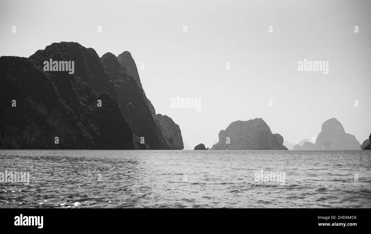 Photo en niveaux de gris de falaises abruptes dans la mer ; exploration du parc national Ao Phang Nga en Thaïlande Banque D'Images