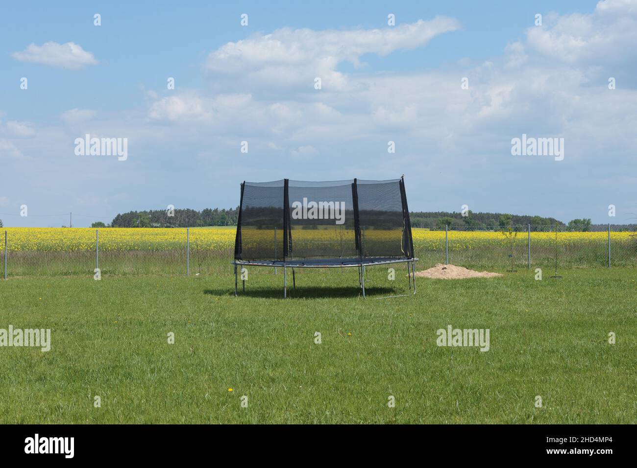 Trampoline pour enfants avec filet d'enclos dans un champ d'herbe Banque D'Images