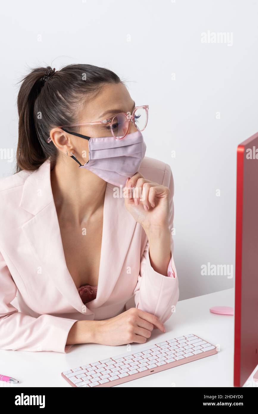 Salisbury, Wiltshire, Royaume-Uni.2021. Femme attrayante portant un masque rose et utilisant un ordinateur et un clavier. Banque D'Images