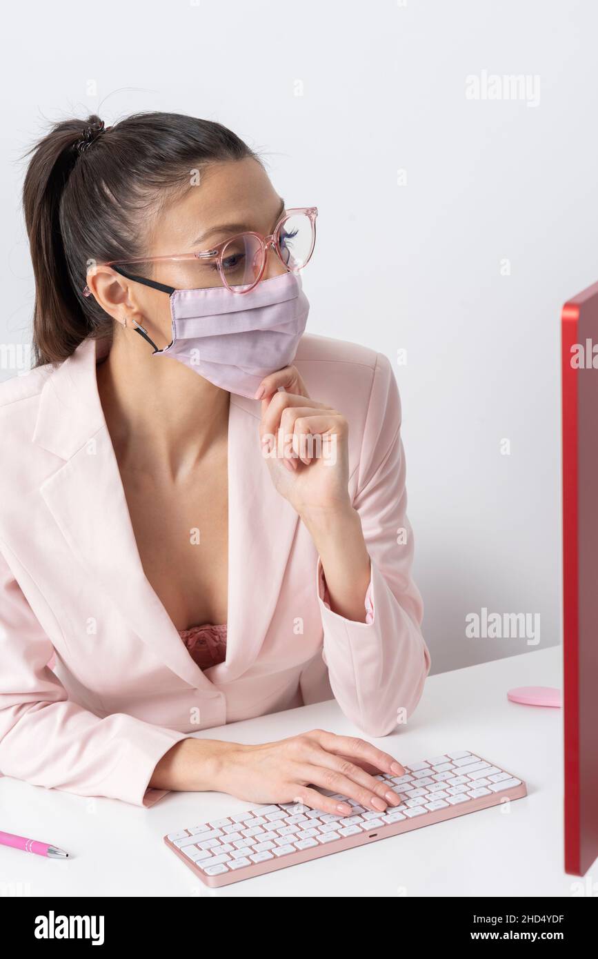 Salisbury, Wiltshire, Royaume-Uni.2021. Femme attrayante portant un masque rose et utilisant un ordinateur et un clavier. Banque D'Images