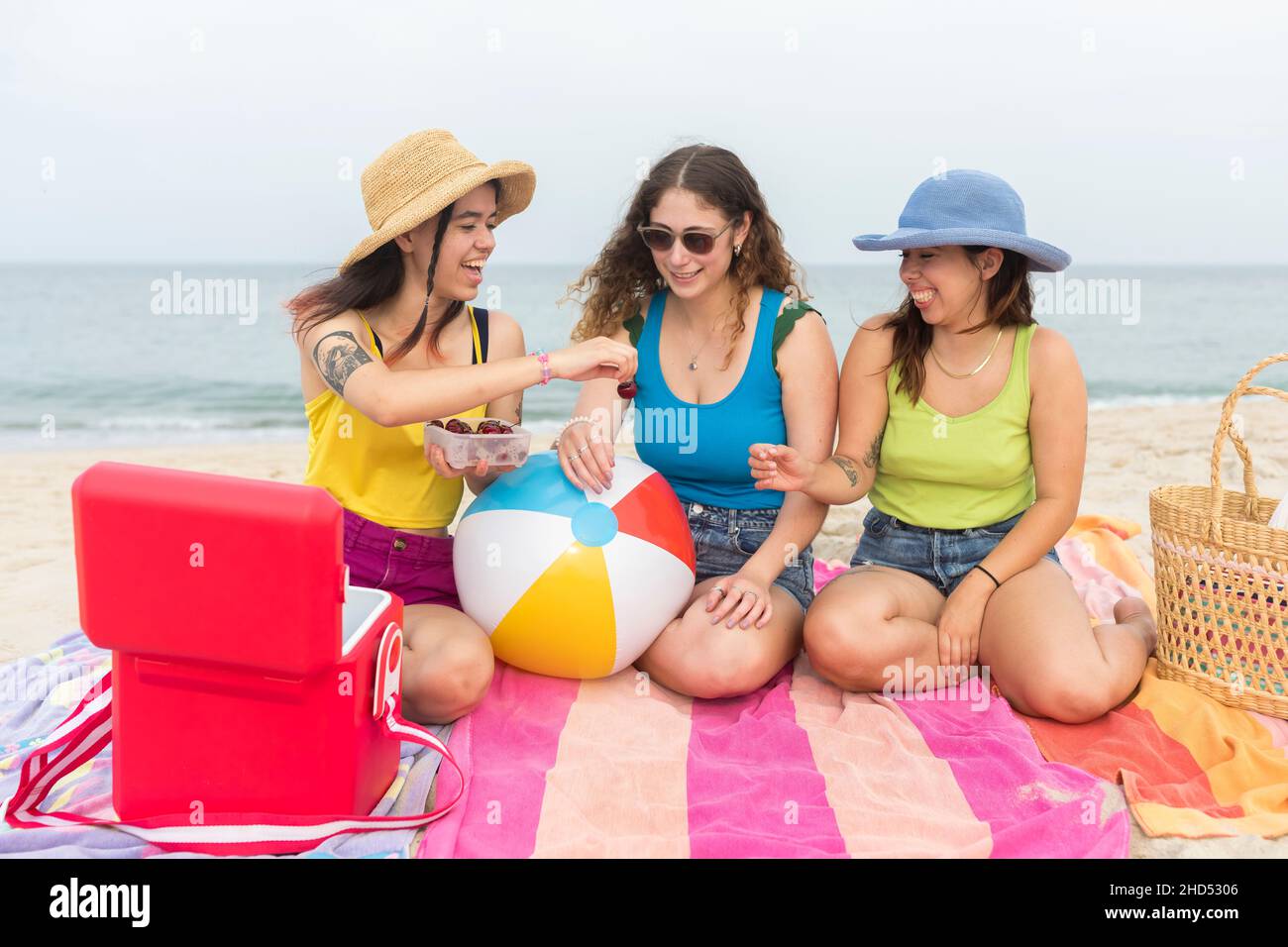 Trois amies d'âge universitaire mangent des cerises à la plage Banque D'Images