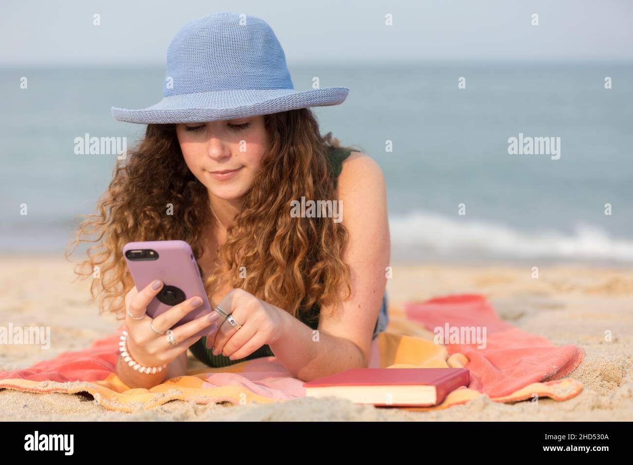 jeune femme à la plage sur une serviette regardant le téléphone portable. Banque D'Images