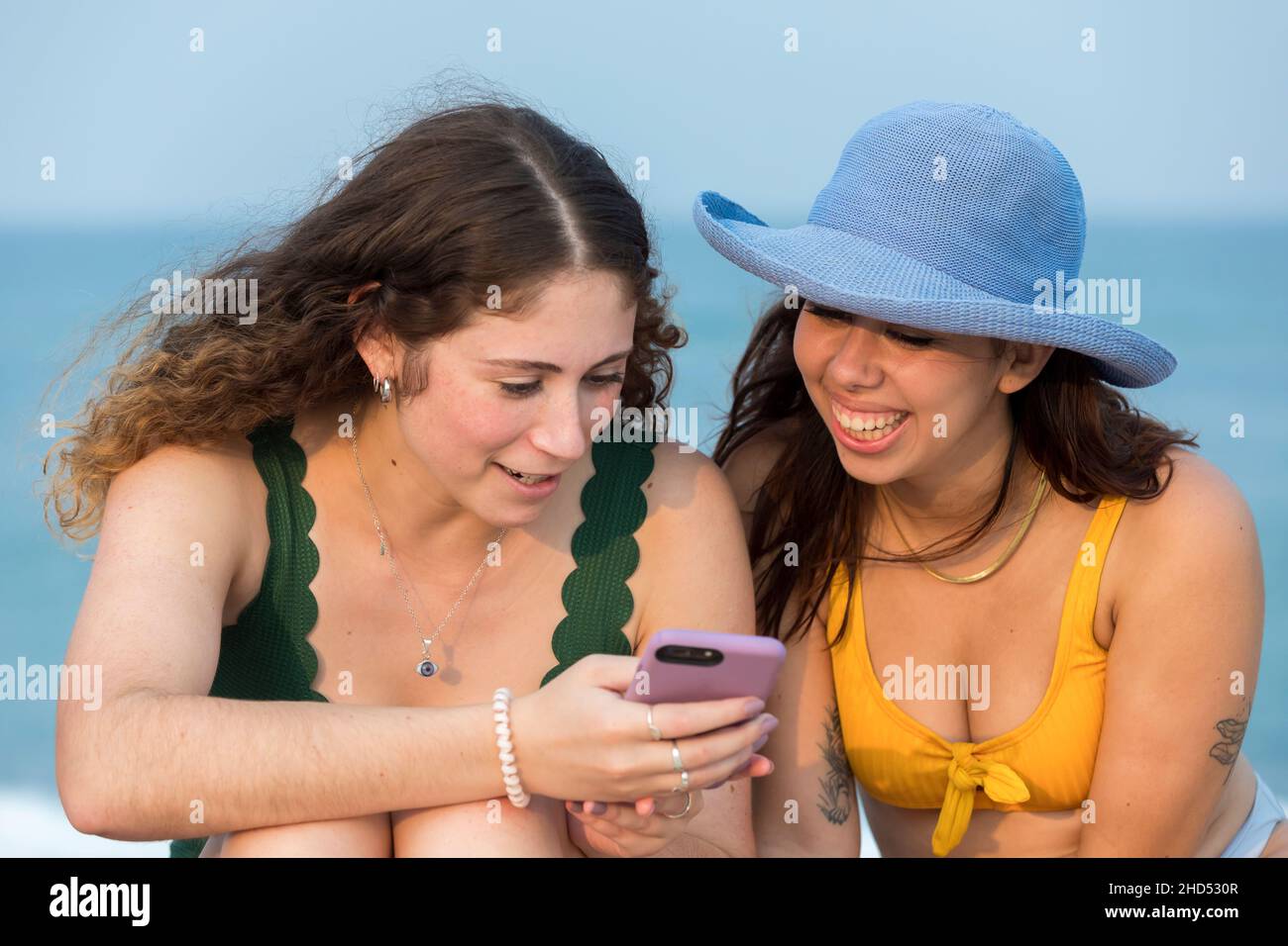 Deux jeunes femmes à la plage regardant le téléphone cellulaire. Banque D'Images