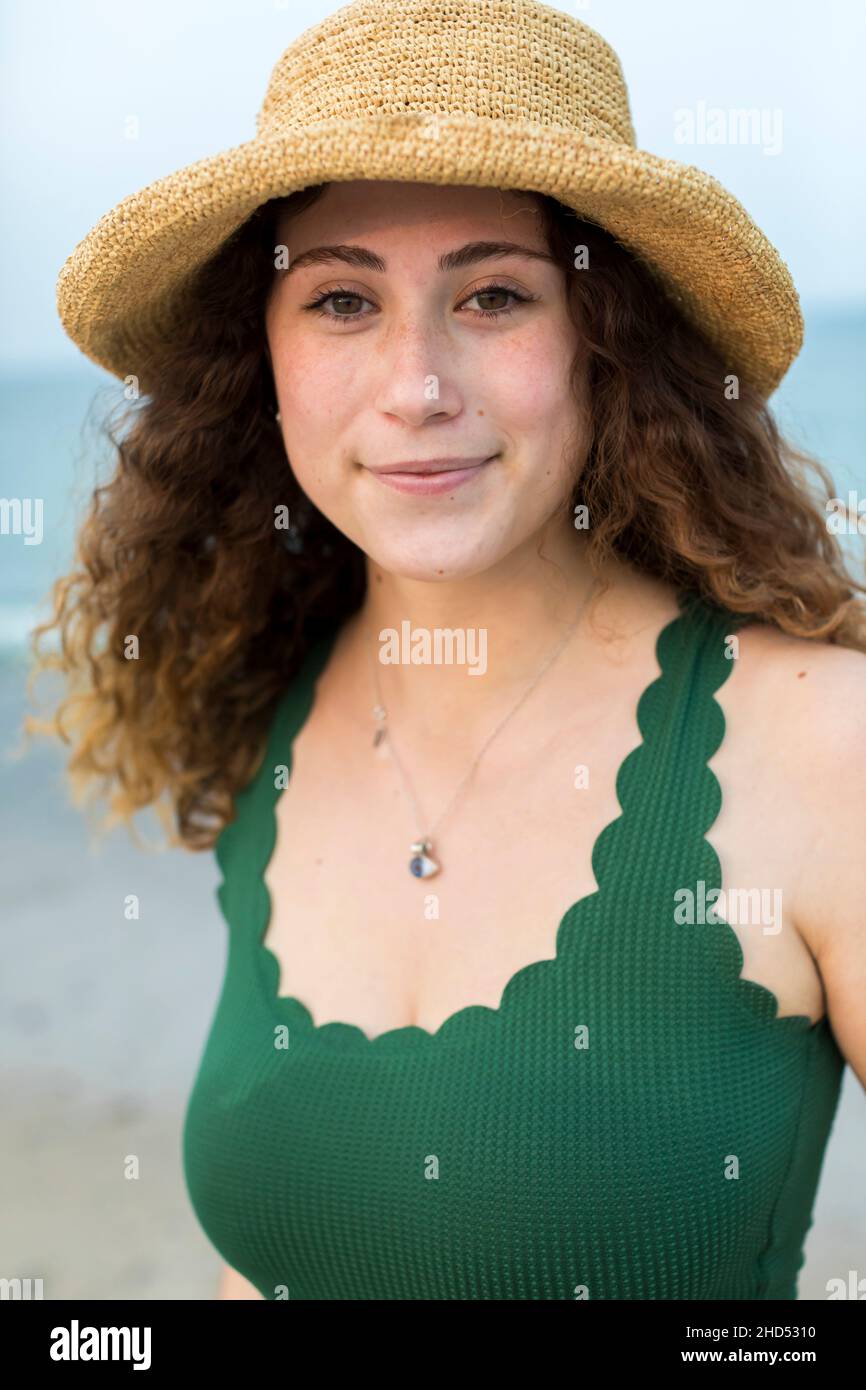 Portrait de la jeune femme à la plage en chapeau et maillot de bain vert Banque D'Images