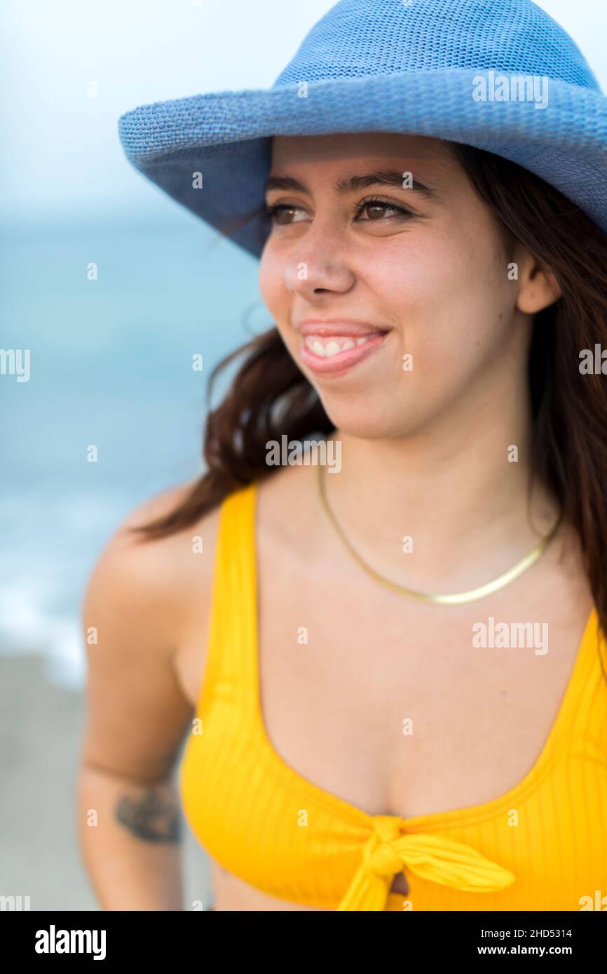 Portrait de la jeune femme à la plage en chapeau bleu et maillot de bain jaune Banque D'Images
