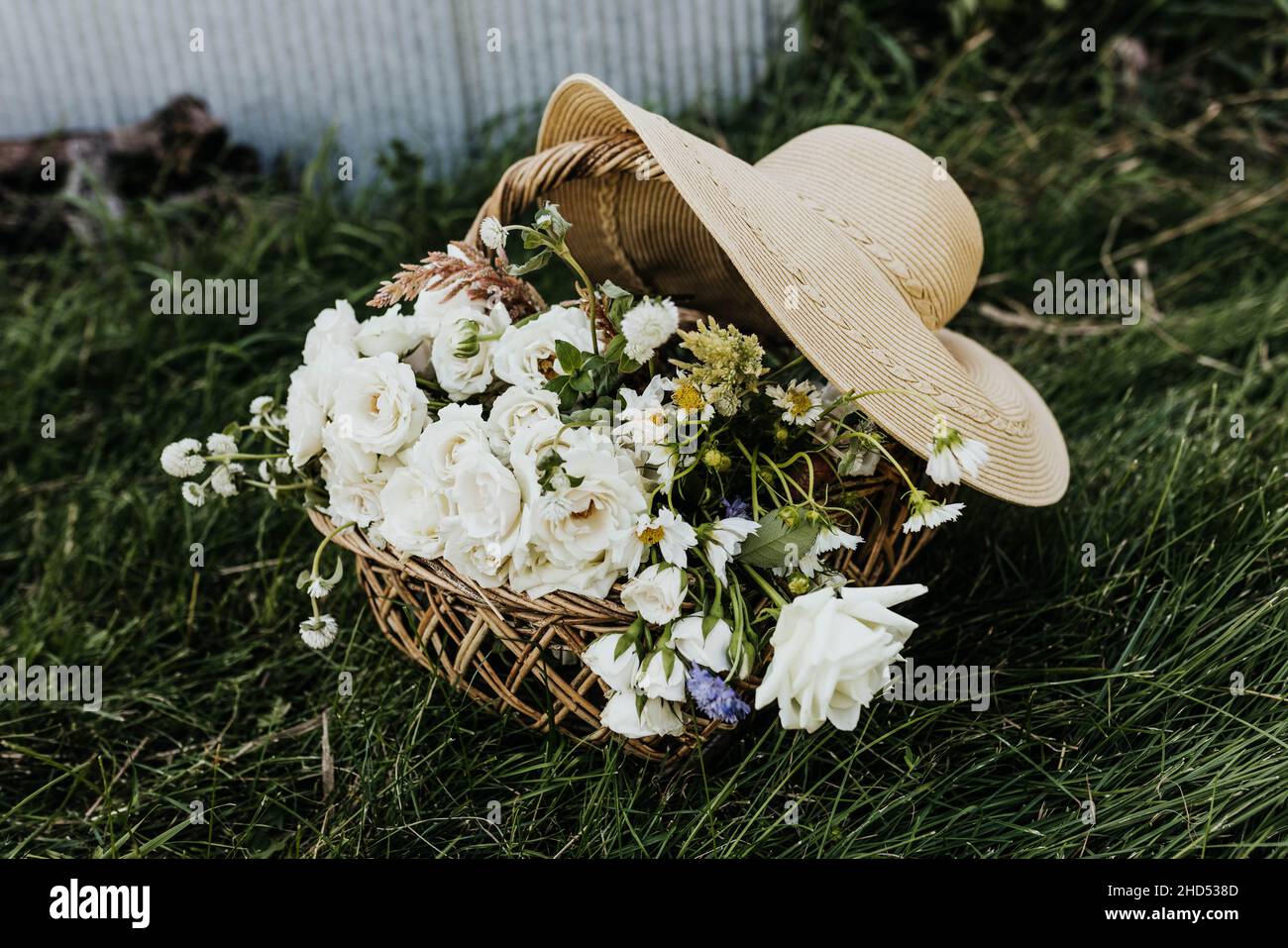 Panier tissé rempli de fleurs sauvages et grand chapeau de soleil Banque D'Images