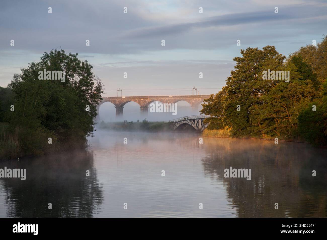 Brumeux lever de soleil d'été au viaduc de Dutton transportant la ligne principale de la côte ouest au-dessus de la navigation de Weaver, au nord d'Acton Bridge, Cheshire Banque D'Images