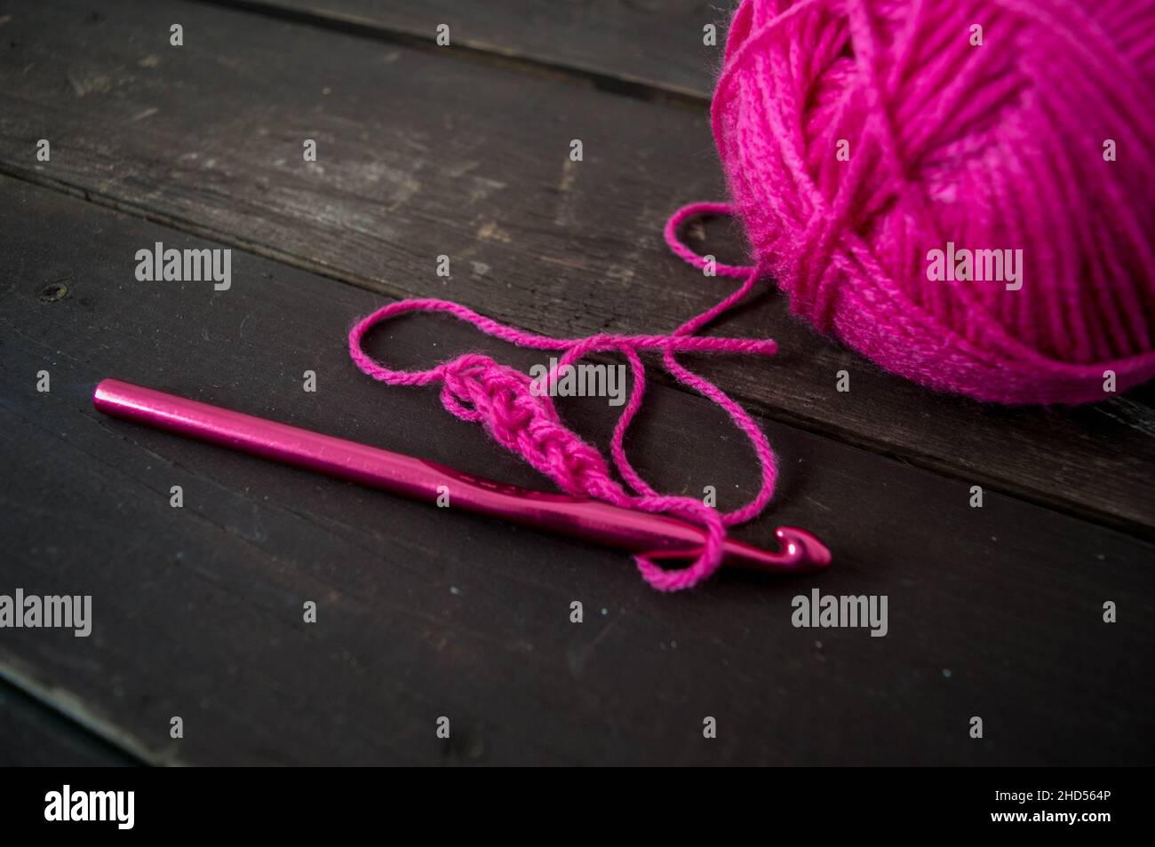 boule de laine rose gros plan avec crochet de crochet rose sur bois moulu fait à la main Banque D'Images