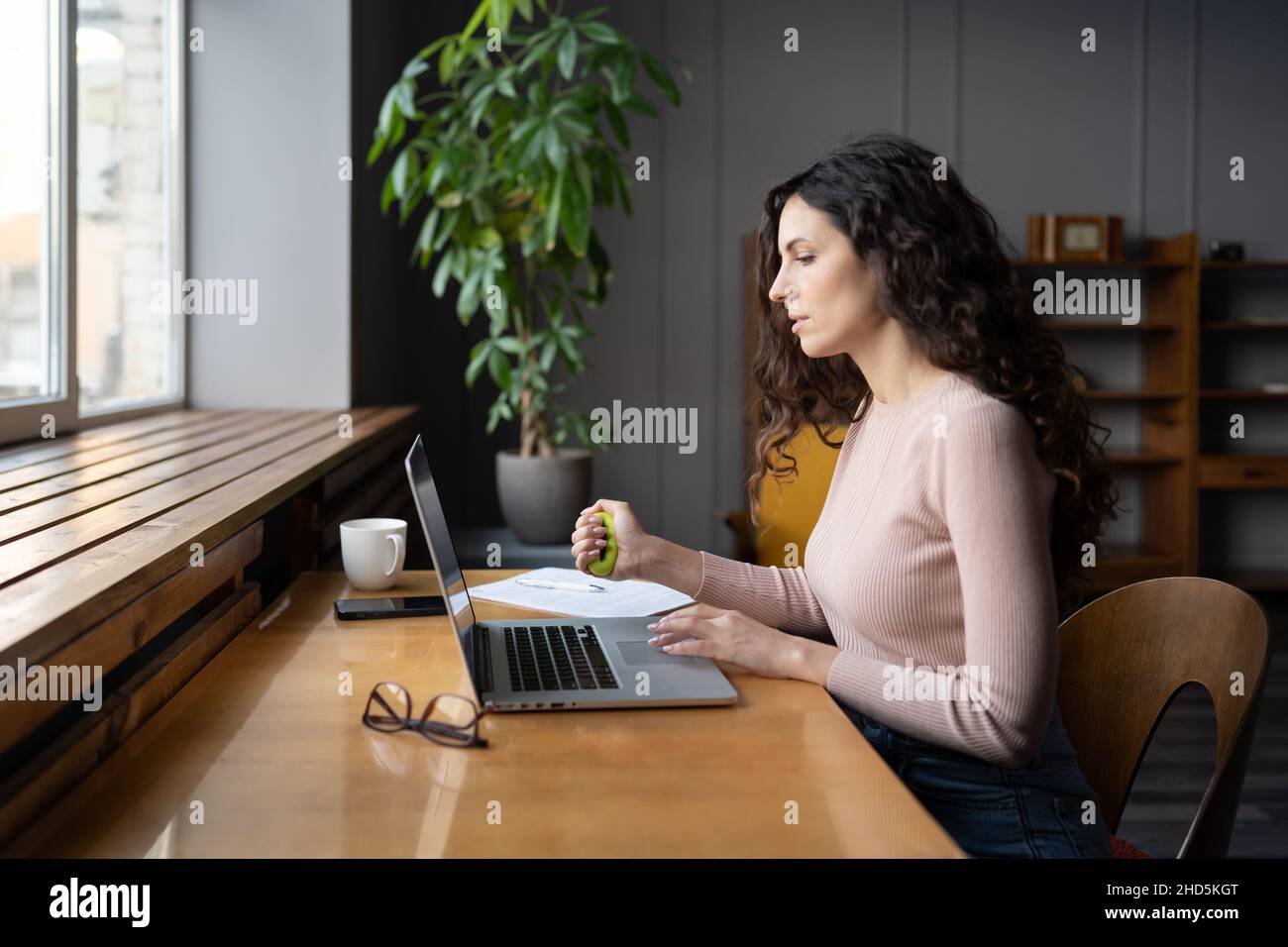 Jeune employée travaillant sur ordinateur portable et faisant des exercices à la main pour prévenir le syndrome du tunnel carpien Banque D'Images