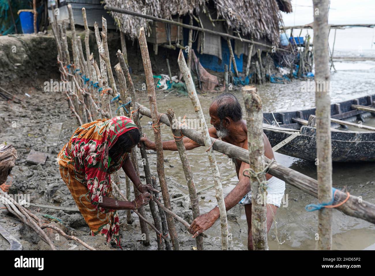 Mongla, Bangladesh.12th septembre 2021.Un vieil homme avec sa femme est en train de rétablir la barrière pour protéger l'embarquement qui a été brisé par les marées hautes dans la zone côtière du village de Jaymani. Le Bangladesh est l'un des pays les plus vulnérables aux effets du changement climatique.Les dangers naturels réguliers et graves que le Bangladesh souffre déjà de cyclones tropicaux, de marées hautes, d'érosion des rivières, d'inondations, de glissements de terrain et de sécheresse sont tous sur le point d'augmenter en intensité et en fréquence en raison du changement climatique.(Photo par Sultan Mahmud Mukut/SOPA image/Sipa USA) crédit: SIPA USA/Alay Live News Banque D'Images