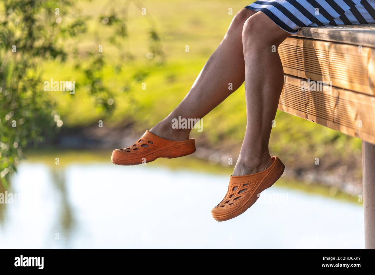 une femme est assise sur le bord d'une passerelle et balance ses jambes sur l'eau du lac Banque D'Images