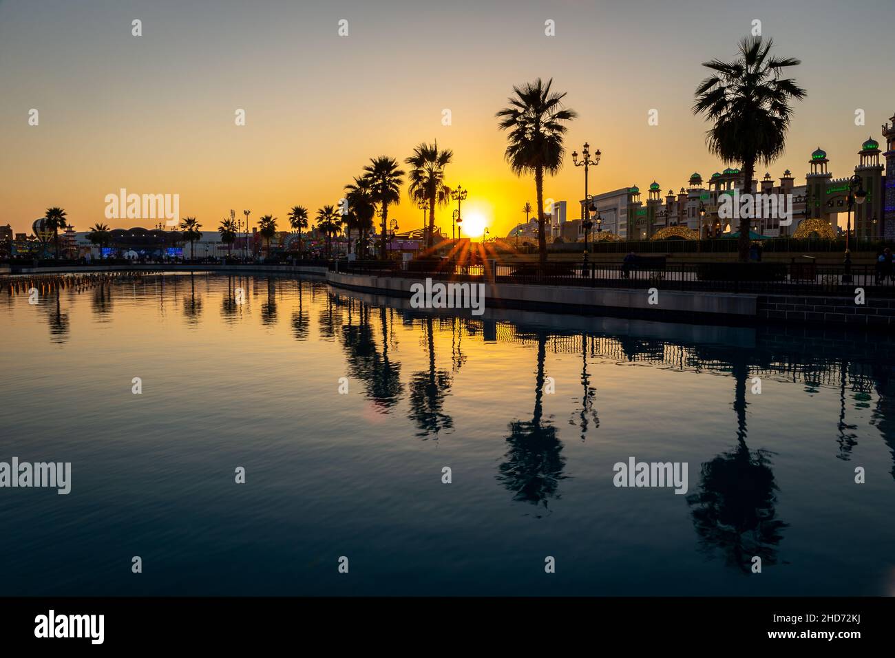 Dubaï, Émirats arabes Unis, 10.01.21.Parc d'attractions de Global Village à Dubaï au coucher du soleil avec une rangée de silhouettes de palmiers reflétant dans l'eau douce. Banque D'Images