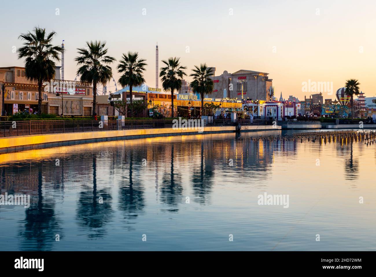 Dubaï, Émirats arabes Unis, 10.01.21.Parc d'attractions Global Village à Dubaï au coucher du soleil avec rangée de palmiers reflétant dans l'eau douce. Banque D'Images