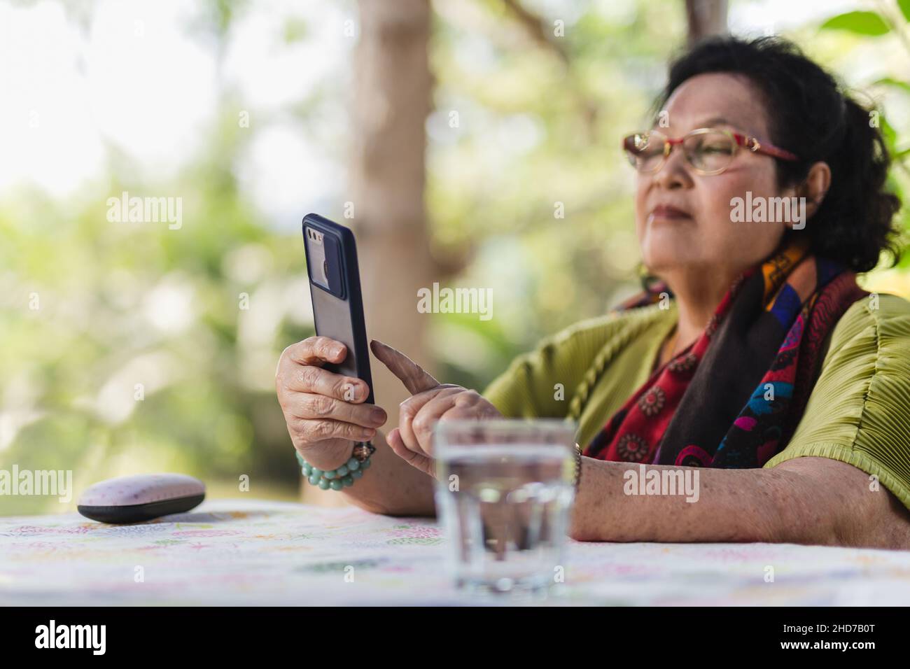 Femme âgée utilisant un smartphone à l'extérieur dans le jardin. Banque D'Images