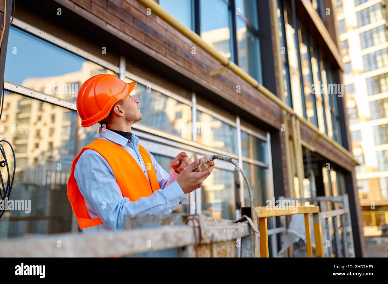 Constructeur grimpant dans le berceau au-dessus de la façade du bâtiment Banque D'Images