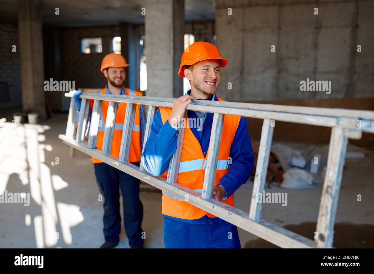 Ouvriers de construction transportant ensemble une échelle en acier Banque D'Images