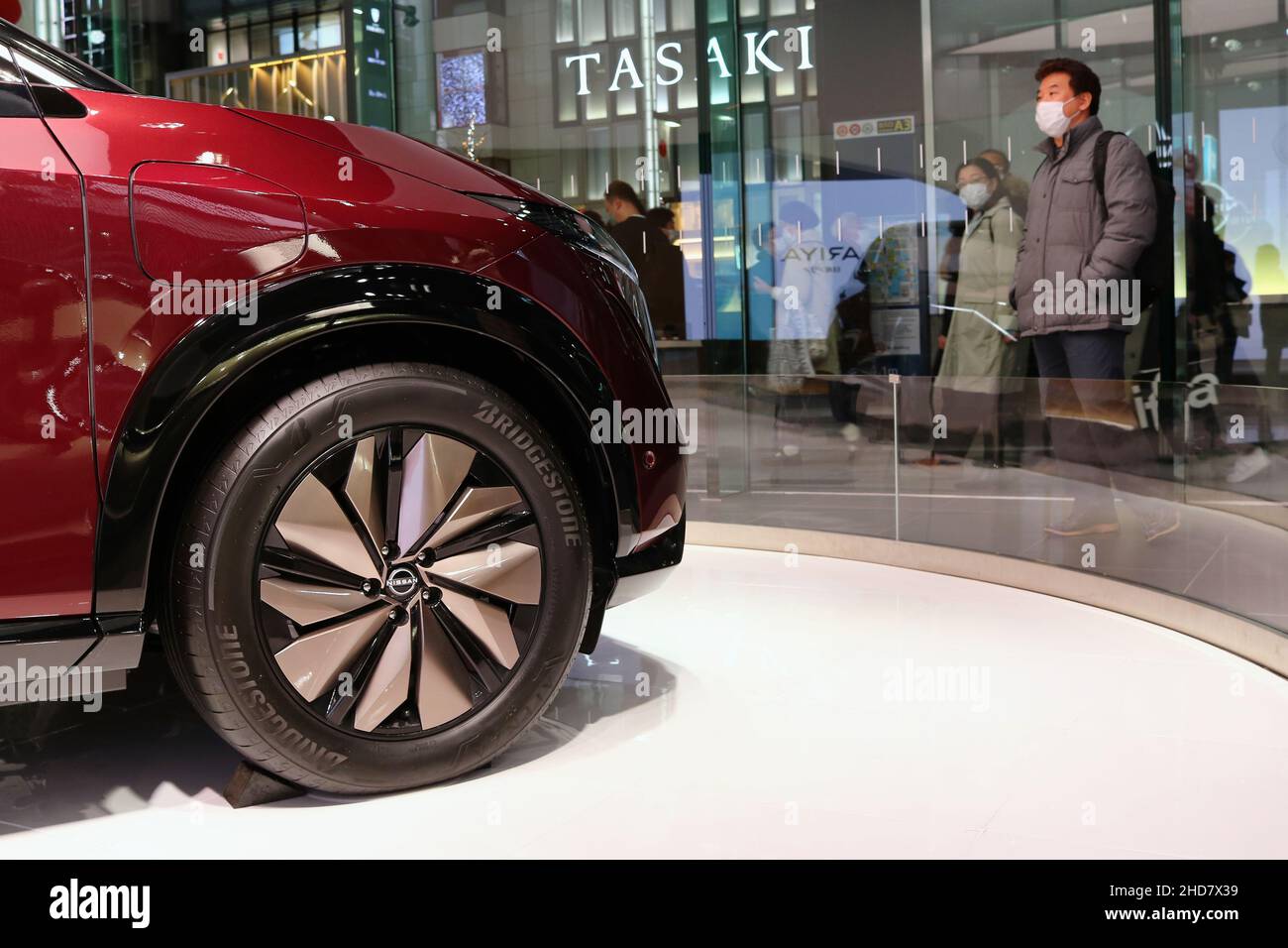 Détail de Nissan Ariya dans la salle d'exposition Ginza place Nissan Crossing de Tokyo avec une rue animée à l'extérieur.Accent sélectif sur la voiture. Banque D'Images