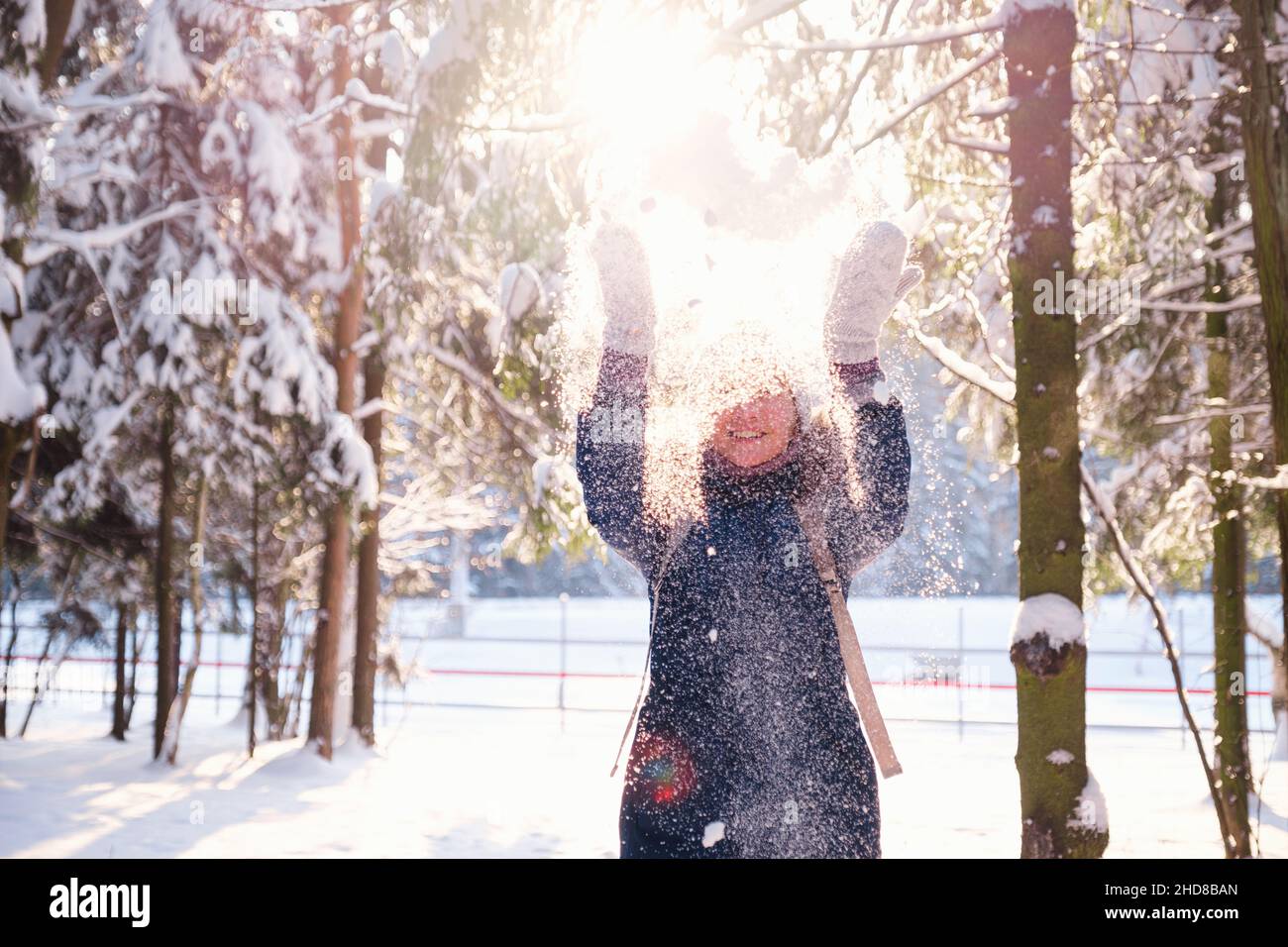 Bonne femme asiatique marchant dans la forêt enneigée d'hiver.Bonne jeune femme joue avec la neige en hiver ensoleillé, profitez de l'hiver, jour gelé. La femme jette de la neige blanche et ample dans l'air. Banque D'Images