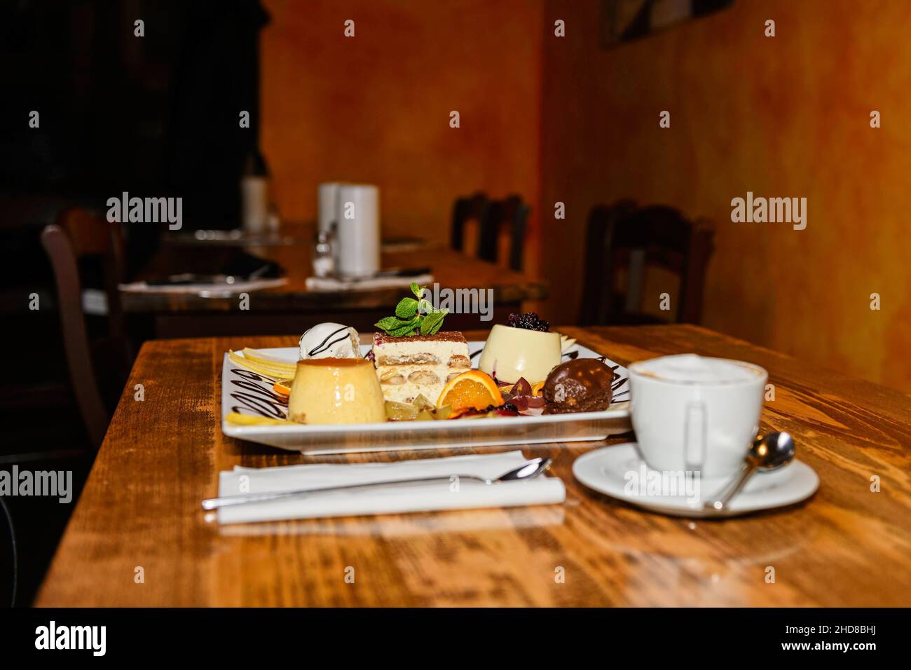 Une sélection de desserts différents, tels que tiramisu et panna cotta, joliment agencés sur une table en bois. Banque D'Images