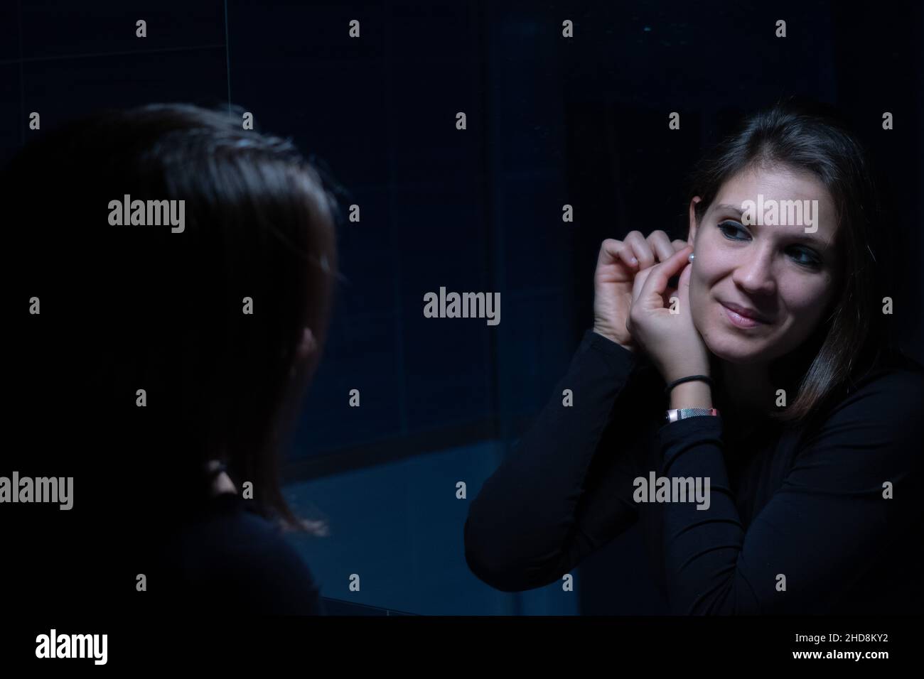 Une jeune femme adulte regardant son visage dans le miroir avant le maquillage Banque D'Images