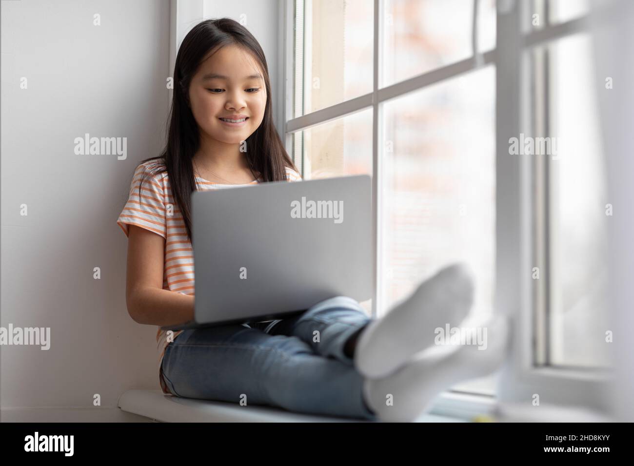 Magnifique enfant chinois utilisant un ordinateur portable, se détendre à la maison Banque D'Images