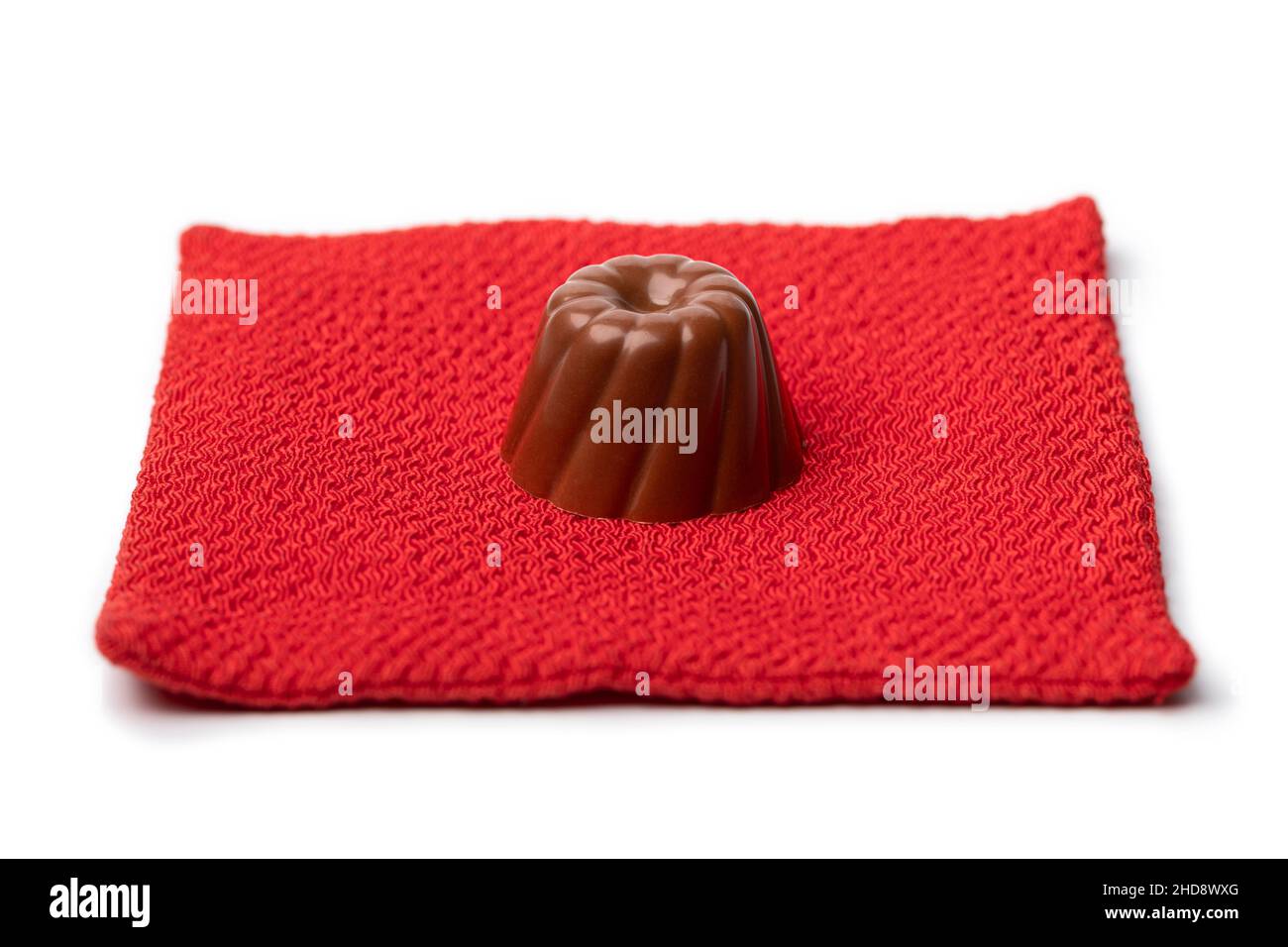Un seul bonbon au chocolat sur un coussin rouge isolé sur fond blanc gros plan Banque D'Images