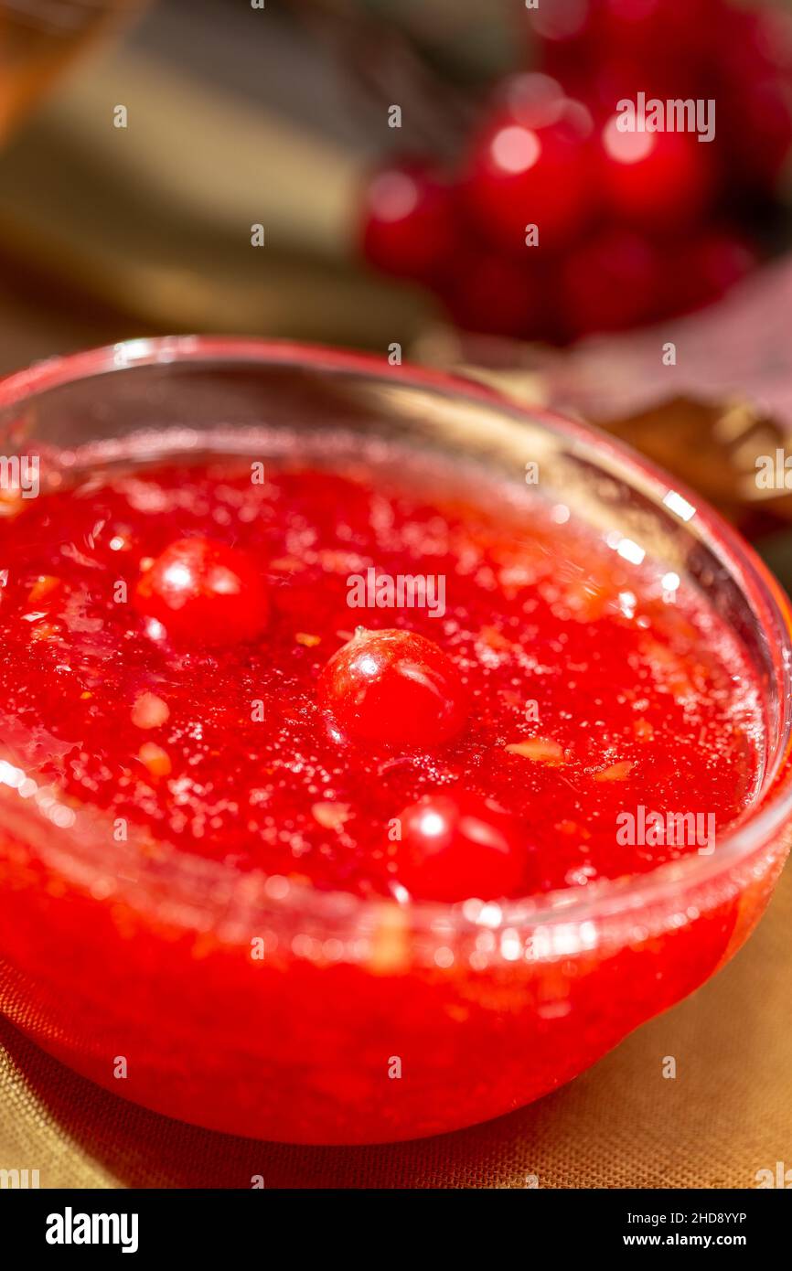 Confiture de viburnum dans un bol en verre sur la table en bois de style rustique avec une boisson chaude d'hiver et des baies de viburnum Banque D'Images