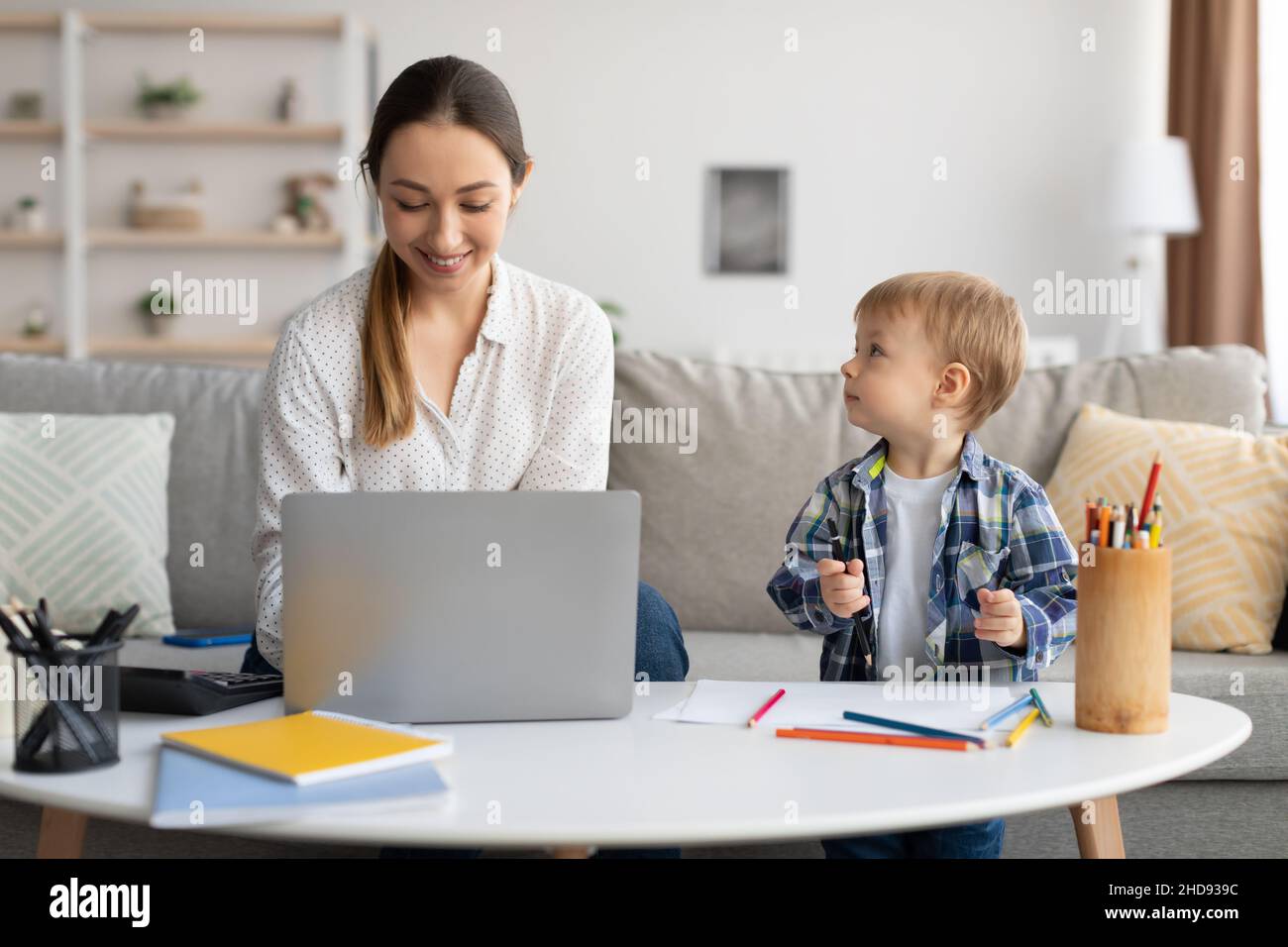 Adorable petit garçon dessin à côté de maman travaillant sur ordinateur portable, femme passant du temps avec son fils et appréciant le travail indépendant Banque D'Images