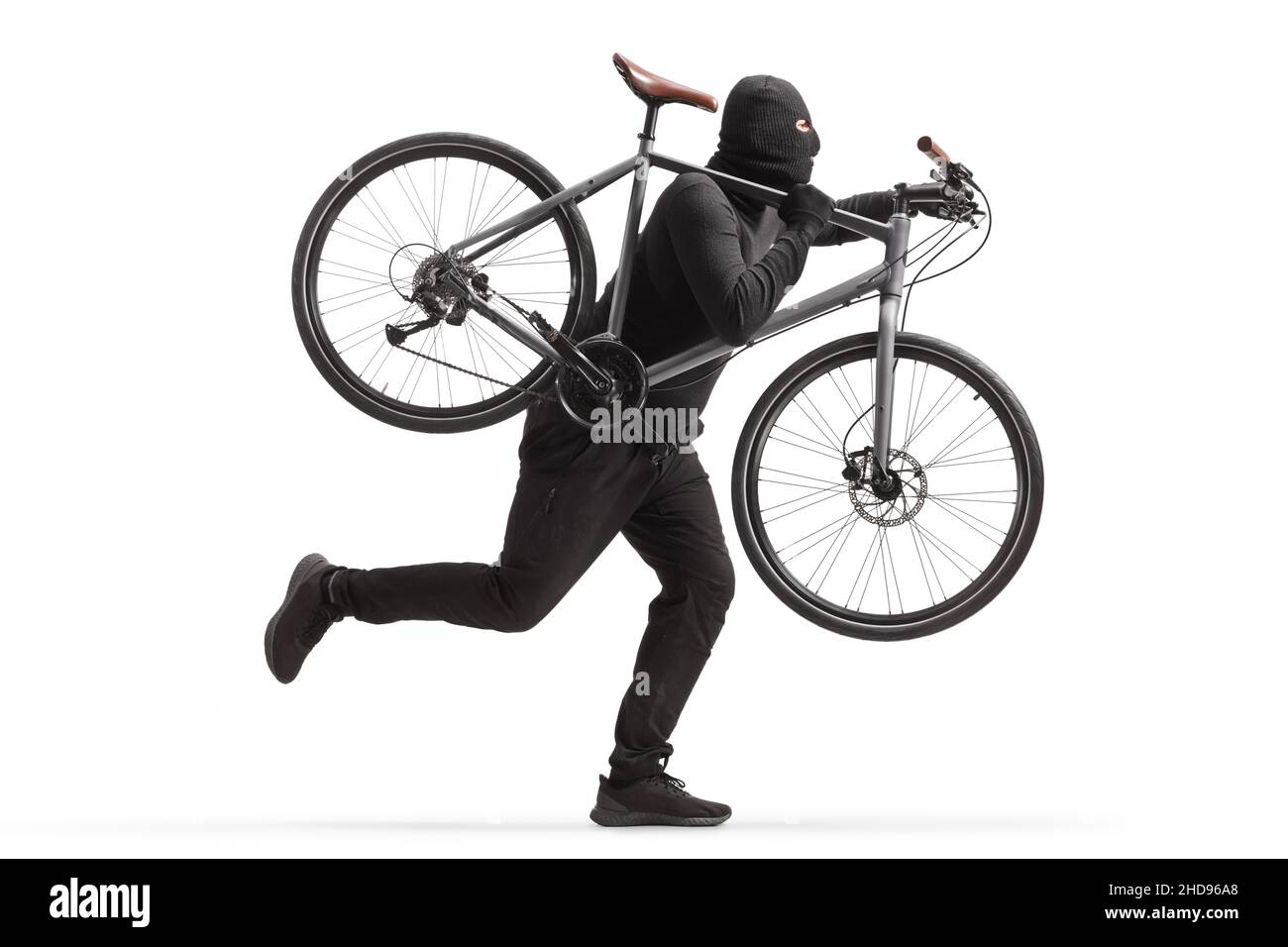 Homme en vêtements noirs et balaclava voler un vélo et courir isolé sur fond blanc Banque D'Images