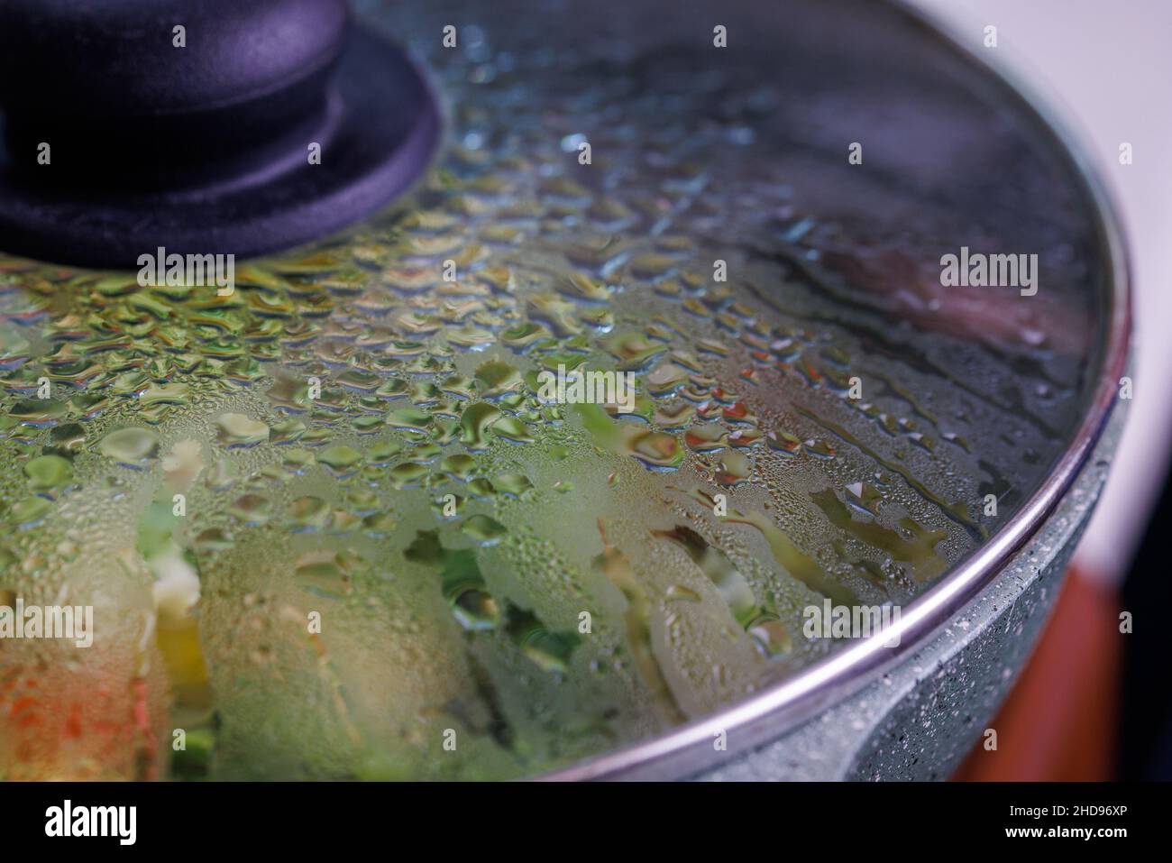 légumes dans une poêle à frire recouverts d'un couvercle en verre avec gouttes de condensation d'eau sur la surface interne, concept abstrait de gros plan Banque D'Images
