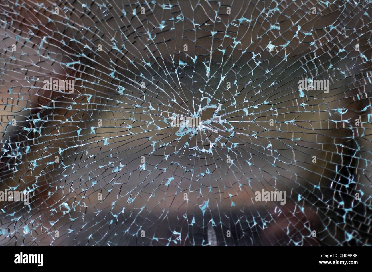 Vitre de voiture cassée avec un motif de verre fissuré et un trou de balle au milieu. Banque D'Images