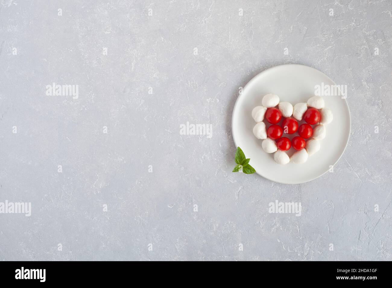 Tomates cerises et mozzarella en forme de coeur, concept de cuisine facile pour la Saint-Valentin, vue du dessus, espace copie Banque D'Images