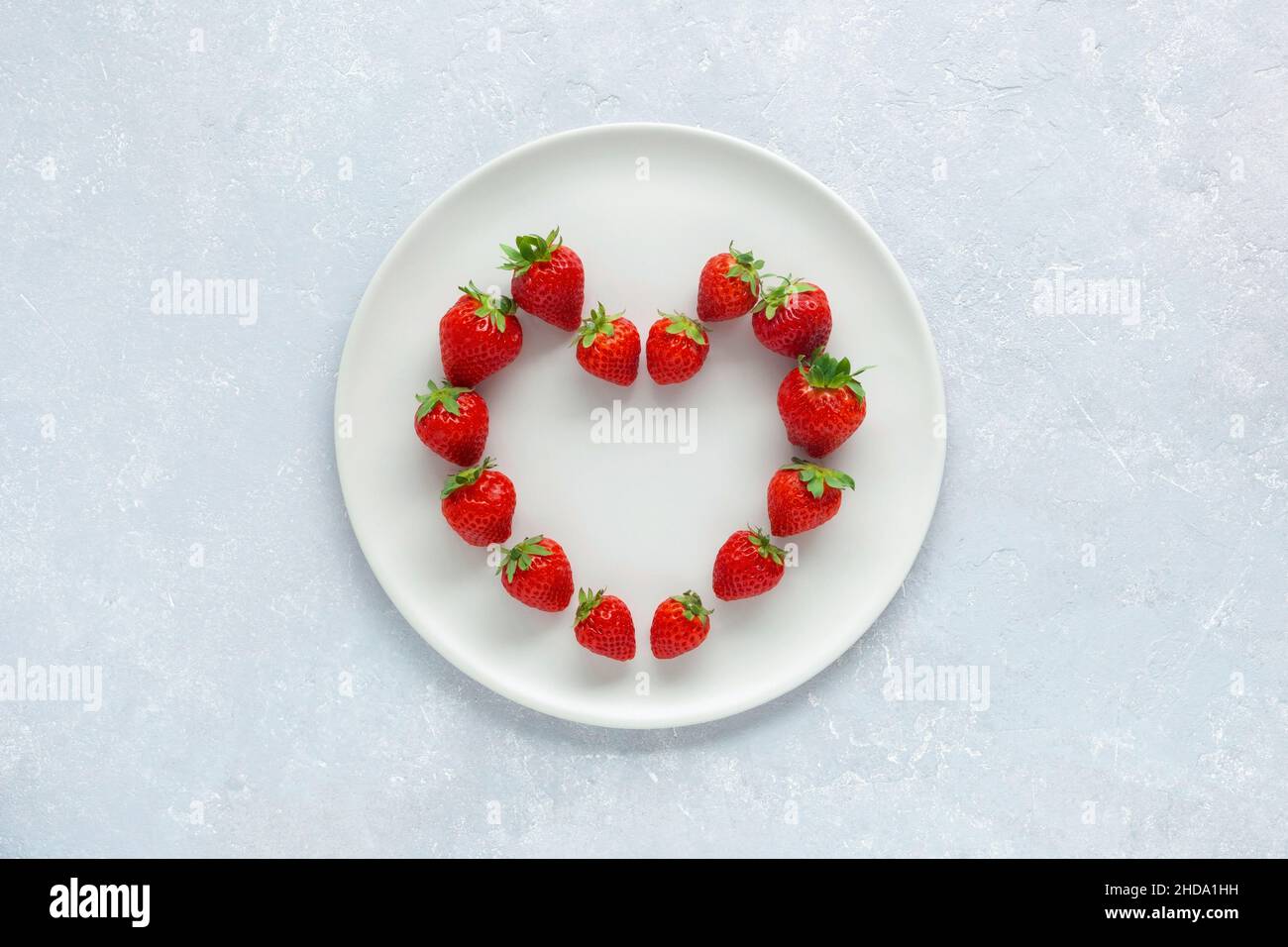 Assiette blanche avec fraises en forme de coeur, concept de la Saint-Valentin, vue du dessus Banque D'Images