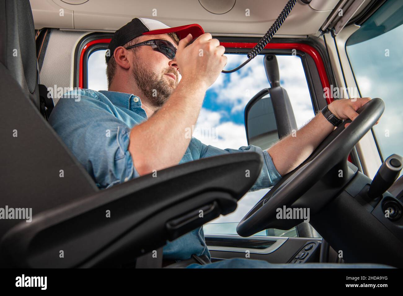 Semi-conducteur de camion parlant sur la radio CB tout en conduisant dans un semi-remorque moderne.Thème de l'industrie du transport. Banque D'Images