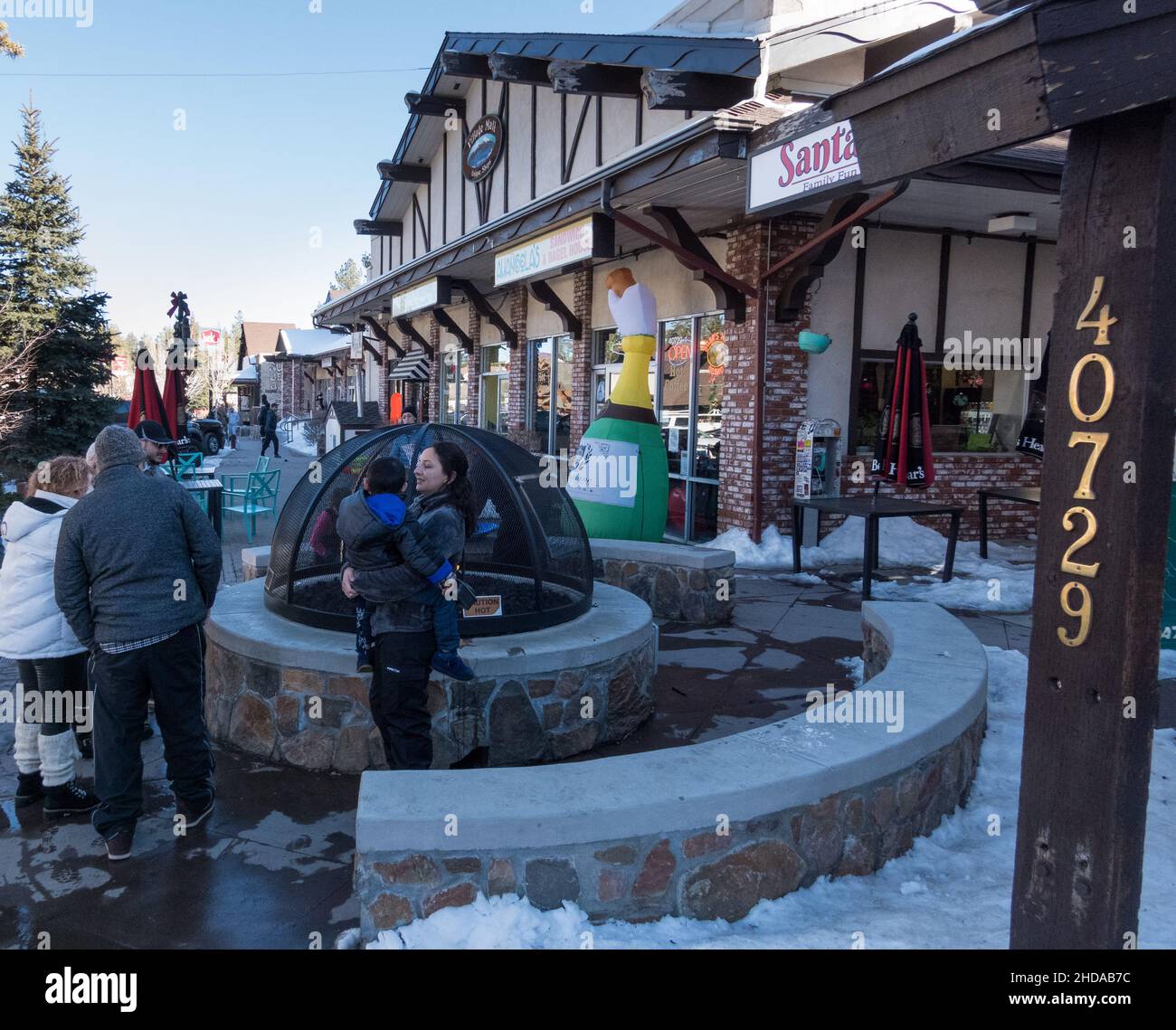 Les gens se réchauffent près de la fosse de feu publique sur le trottoir le long de Village Dr à Big Bear Lake, Californie, États-Unis Banque D'Images
