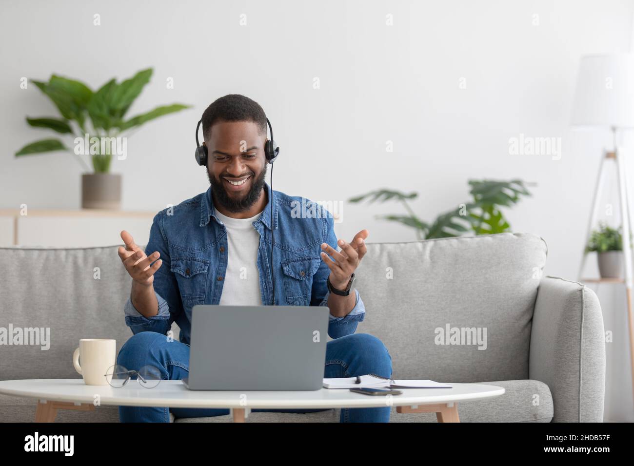 Joyeux et heureux jeune homme d'affaires noir, professeur avec barbe dans un casque avec pc gestante avec les mains Banque D'Images