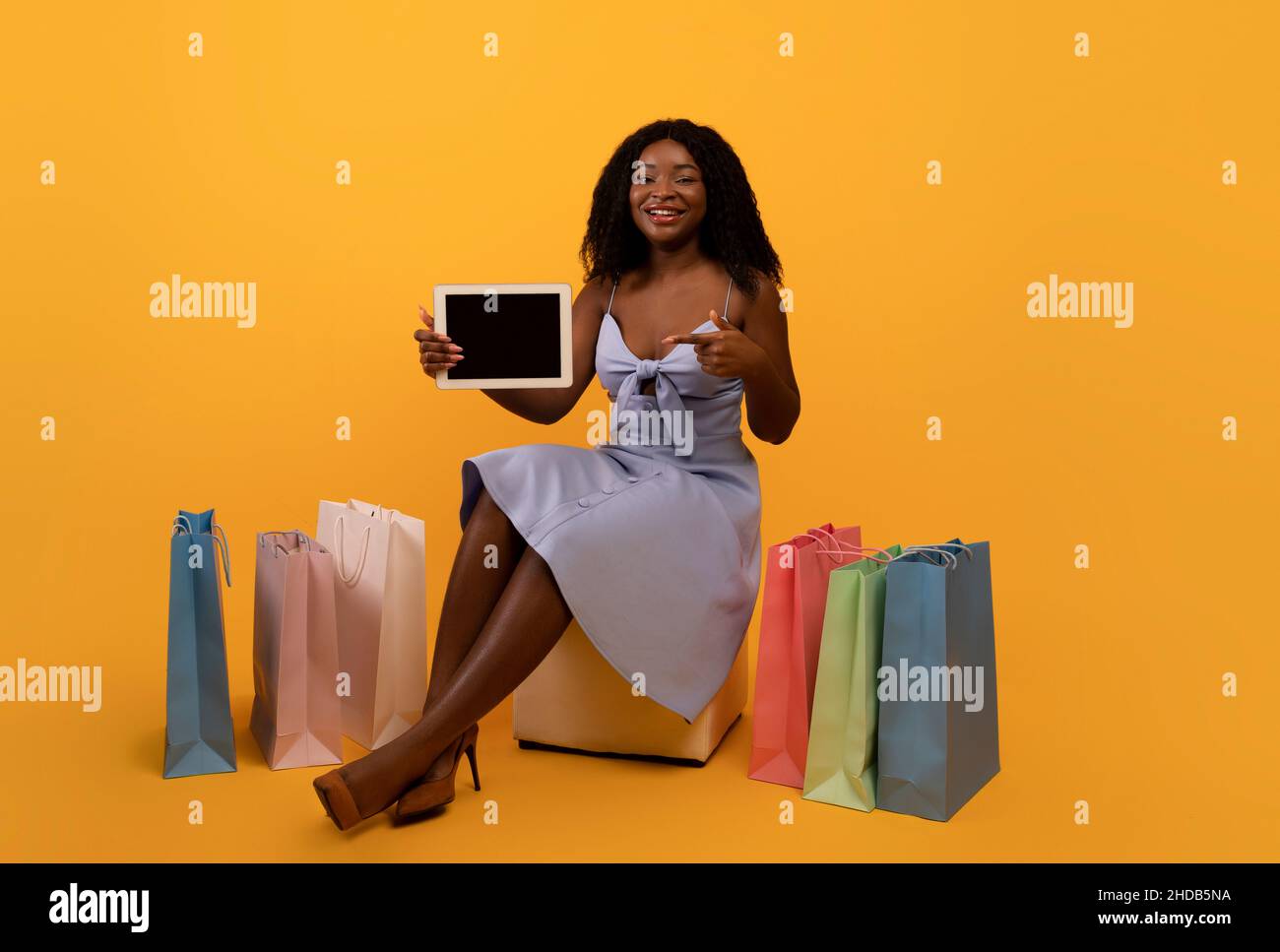 Femme noire millénaire montrant une tablette numérique avec écran vide, offrant une maquette pour une nouvelle application ou un nouveau site Web, des achats en ligne Banque D'Images